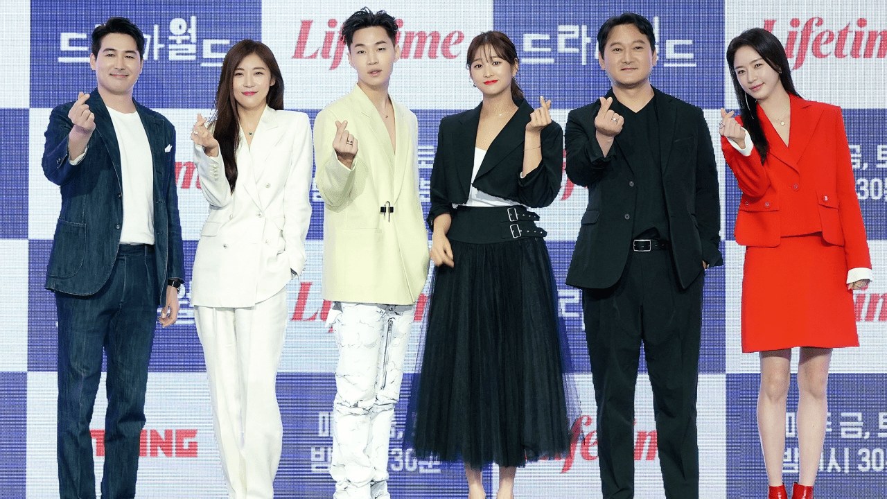 Six cast members making finger hearts at the Dramaworld 2 launch press conference in Korea
