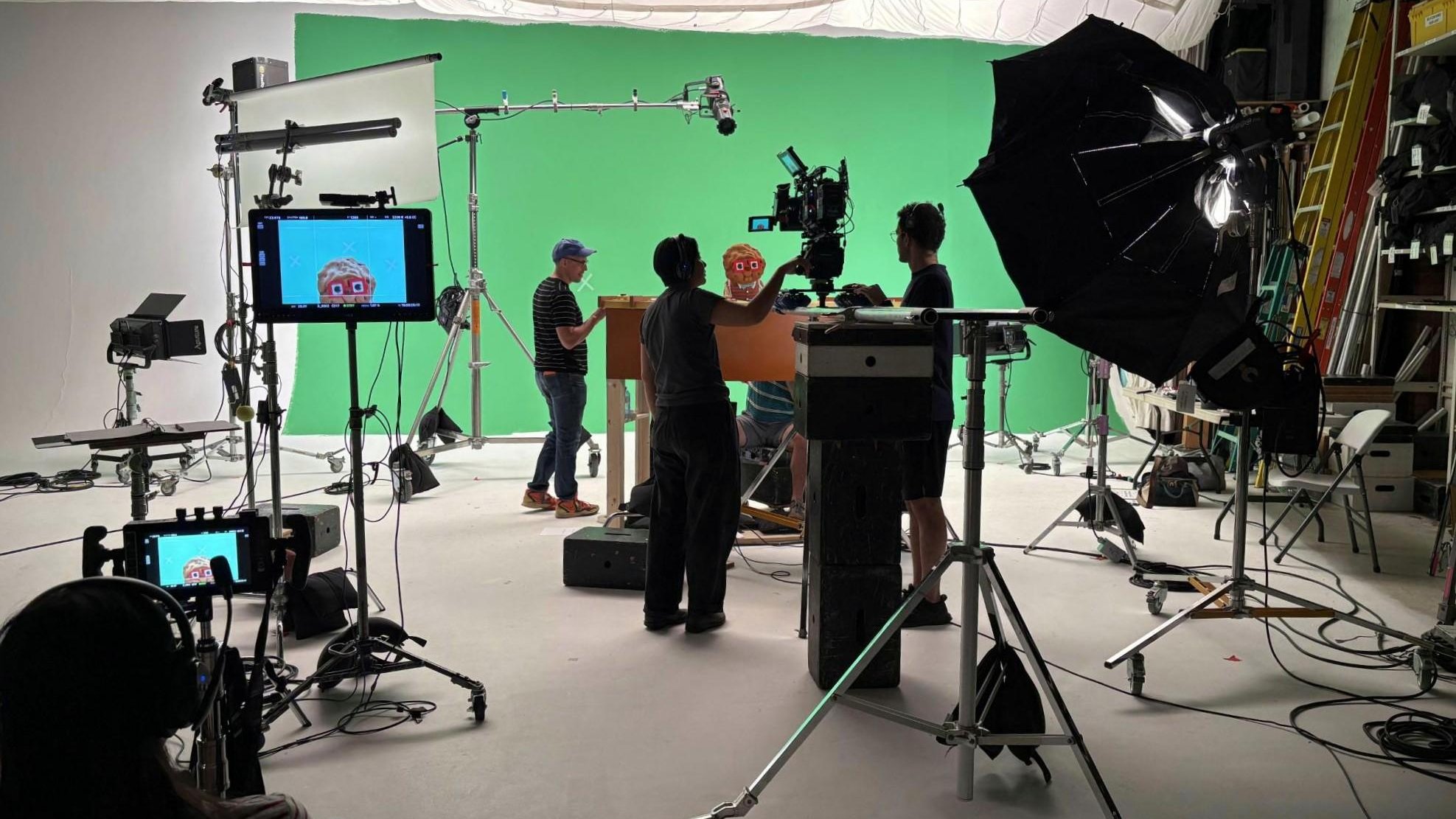 On the green-screen stage: the crew lines up a shot of the Chip puppet behind the console, with Chip on the monitors